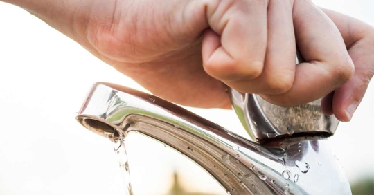 person shutting off a faucet